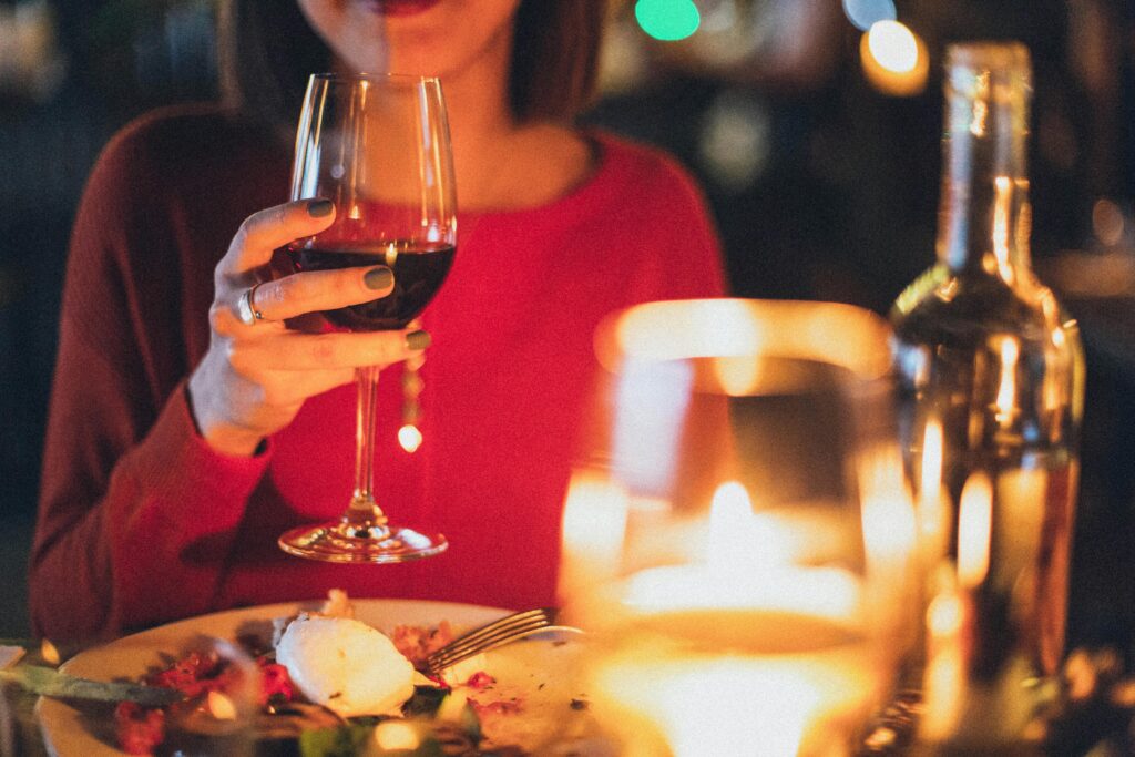 Unique Experiences at SV Luxe Resort, Munnar – Luxury Beyond Ordinary A woman enjoying red wine at a romantic candlelit dinner, perfect for celebrations.